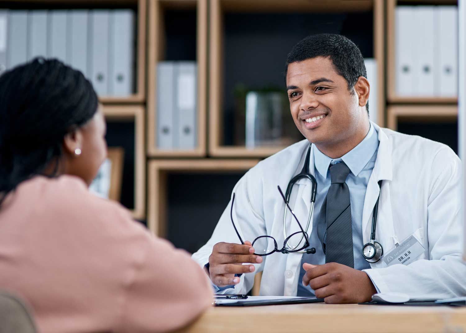 A woman sits on an exam table and talks to a nurse