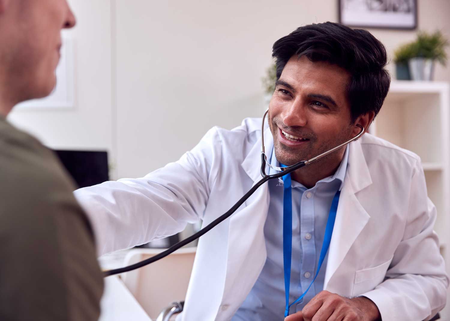 A woman sits on an exam table and talks to a nurse